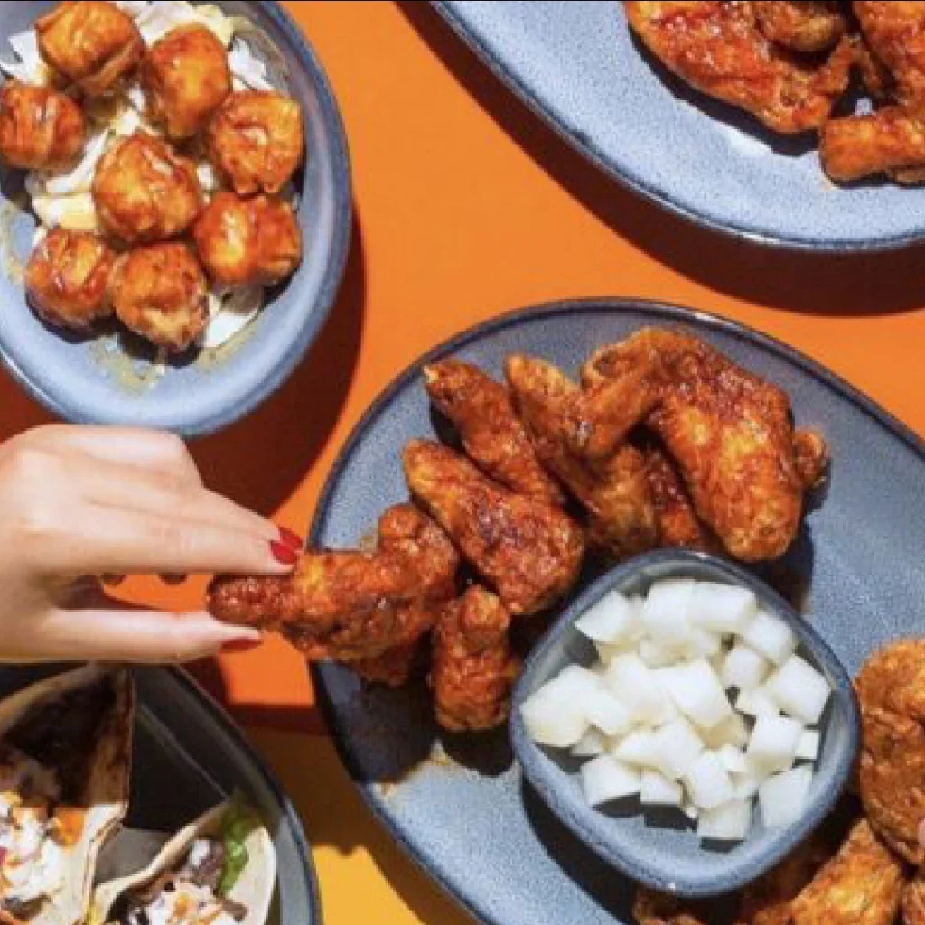 Person reaches for wings prepared at Bonchon at Merriweather District, Columbia, Maryland.