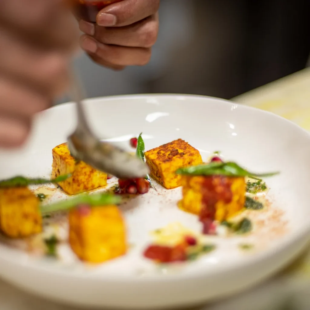 Chef prepares plate of food at Clove & Cardamom.