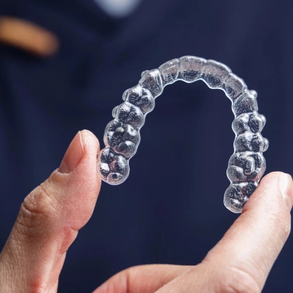 Person holds an Invisalign retainer.