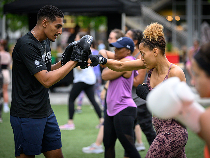 Summer Fit Series: Mayweather Boxing + Fitness A woman boxes with a trainer from Mayweather Boxing at an event at Merriweather District.