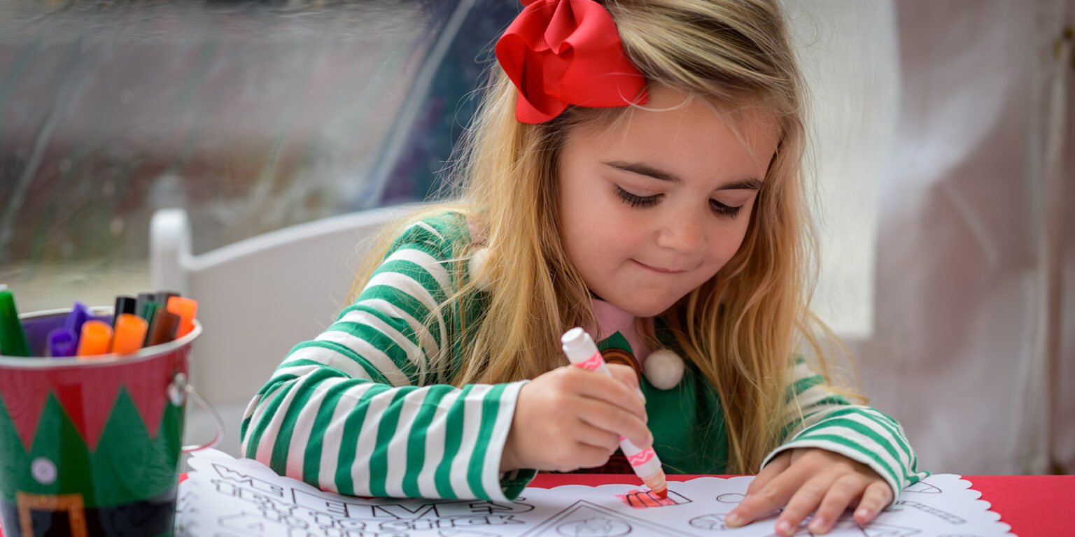 Child colors with marker at the Holiday Market & Tree Lighting.