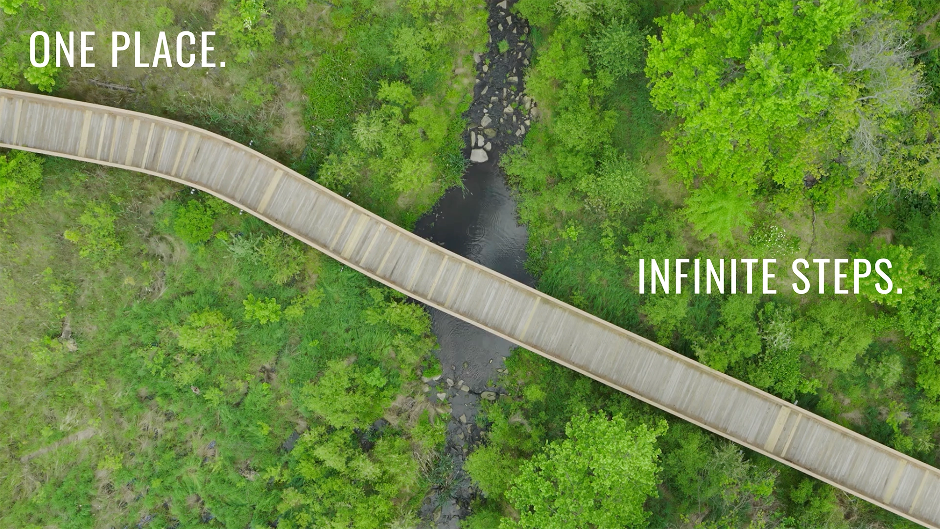 Overhead view of a wooden path at Merriweather District. Text reads "one place. infinite steps."