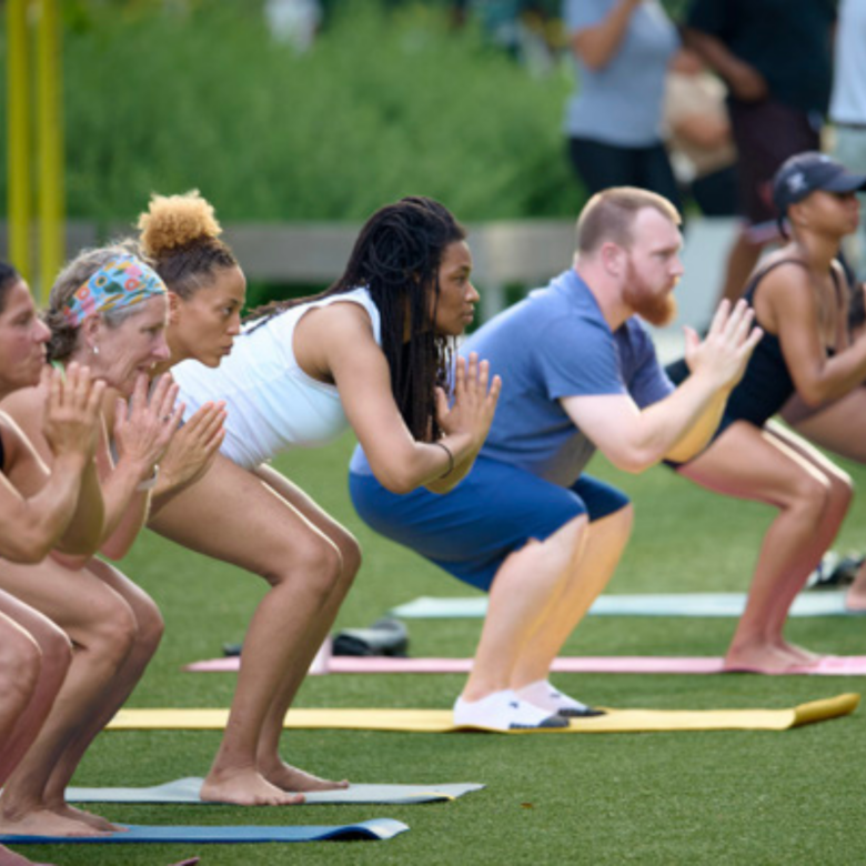 Diverse group of women and men yogis practicing chair pose outdoors